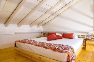1 dormitorio con 1 cama blanca grande con almohadas rojas en Lavrio stone house 5 min from the centre/port, en Lávrion