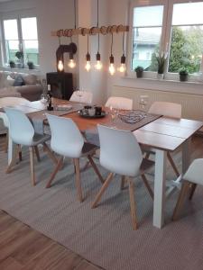 a dining room with a wooden table and white chairs at "Heimathafen" mit Sauna in Hohenkirchen