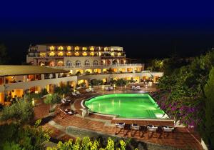a large building with a swimming pool at night at Out Of The Blue Resort & Spa in Agia Pelagia