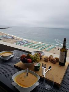 a table with a plate of food and a bottle of wine at Beach front - sea and sunset views in Póvoa de Varzim