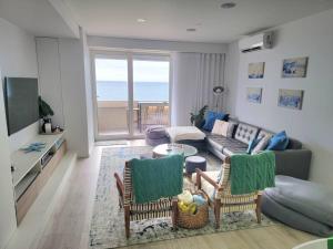 a living room with a couch and a table and chairs at Beach front - sea and sunset views in Póvoa de Varzim