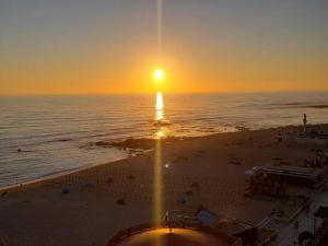 a sunset on a beach with the sun setting at Beach front - sea and sunset views in Póvoa de Varzim