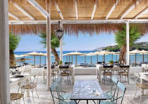 un restaurant avec des tables et des chaises et l'océan dans l'établissement Out Of The Blue Resort & Spa, à Agia Pelagia