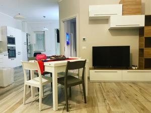 ein Wohnzimmer mit einem Tisch mit Stühlen und einem TV in der Unterkunft MAD casa vacanze Bernalda in Bernalda