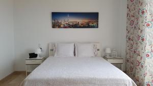una camera da letto con un letto bianco con due comodini e un dipinto di VILLA LORA Modern & New townhouse 2 Bedroom a Puerto de Santiago Altre 42 foto