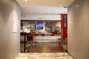 a restaurant with a bar with red stools at Ibis Kaunas Centre in Kaunas