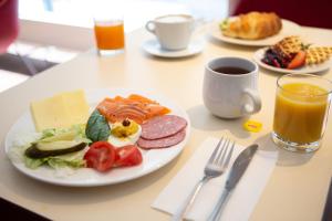 a table with a plate of breakfast food and a cup of coffee at Ibis Kaunas Centre in Kaunas