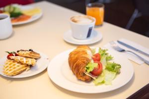a table with plates of food and a cup of coffee at Ibis Kaunas Centre in Kaunas