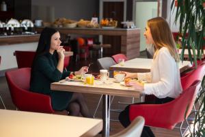 two women sitting at a table in a restaurant at Ibis Kaunas Centre in Kaunas