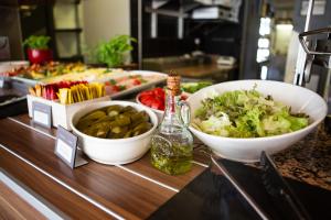 a buffet with bowls of food and a bottle of alcohol at Ibis Kaunas Centre in Kaunas