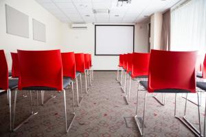 a conference room with red chairs and a white screen at Ibis Kaunas Centre in Kaunas