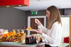 a woman is holding a plate of food at Ibis Kaunas Centre in Kaunas