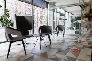 a group of chairs and tables in a room with windows at Ibis Kaunas Centre in Kaunas