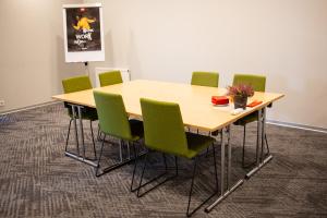 a wooden table with green chairs in a room at Ibis Kaunas Centre in Kaunas