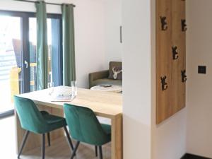 a dining room with a table and two green chairs at BergButzen mit Balkon in Braunlage