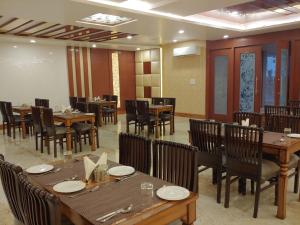 a dining room with wooden tables and chairs at HOTEL SHIVOY GRAND in Varanasi