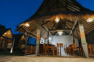 a pavilion with wooden chairs and tables in it at Sundi Hill Cottage in Nusa Penida