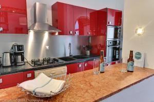 a kitchen with red cabinets and wine bottles on a counter at Villa Lamartine in Aix-les-Bains