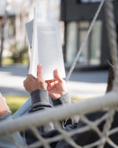 eine Person, die auf einer Schaukel sitzt und ein Buch liest in der Unterkunft Pasaka Palanga in Palanga