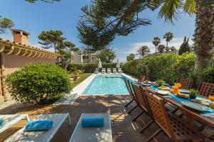 an outdoor dining area with a table and chairs next to a pool at Villa Plomer Serra in Playa de Muro
