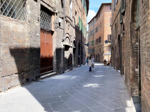 a woman walking down an alley with a dog at WHITE HOUSE STALLOREGGI-vicino alla Cattedrale in Siena