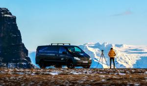 uma pessoa com uma câmara e uma carrinha numa montanha em KúKú Campers - Campervans em Keflavík