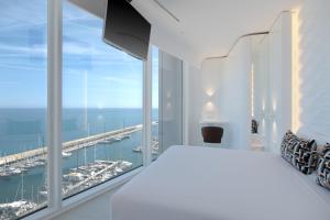 a white bedroom with a view of a harbor at Hotel Marina Badalona in Badalona