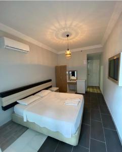 een slaapkamer met een groot wit bed en een televisie bij Günaydın Otel Alanya in Alanya