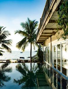 a house with a swimming pool next to the ocean at TW Guaimbê Exclusive Suítes in Ilhabela