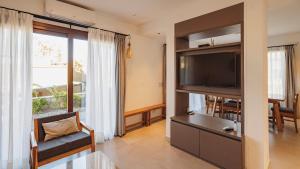 uma sala de estar com uma televisão de ecrã plano e uma cadeira em La Madrina Apart Hotel em Tafí del Valle