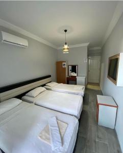 a room with three beds and a television in it at Günaydın Otel Alanya in Alanya