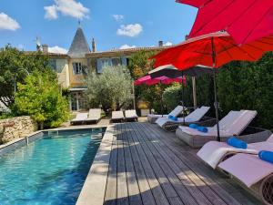 a swimming pool with chairs and a red umbrella at Le Clos R&eacute;aud in Blaye