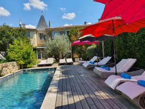 a swimming pool with chairs and a red umbrella at Le Clos Réaud in Blaye