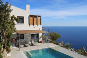 a house with a swimming pool next to the ocean at Anemos Luxury Villas in Rodakino