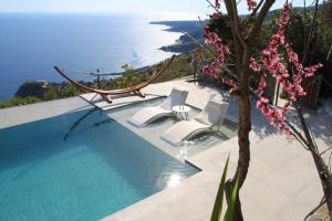 een zwembad met stoelen en uitzicht op de oceaan bij Anemos Luxury Villas in Rodakino