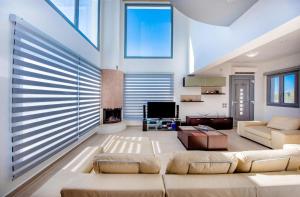 a living room with a couch and a tv at Dias Luxury Villa in Koskinou