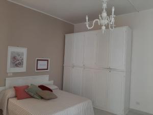 a white bedroom with a bed and a chandelier at La Vie En Rose - Casa vacanze in Diamante