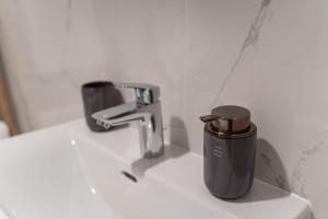 a sink with a faucet and a cup on it at Apartamenty Przystanek Orłowo Centrum in Gdynia