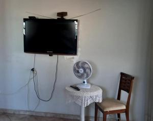 a flat screen tv hanging on a wall with a fan at suítes economy uberlandia in Uberlândia