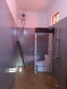 a bathroom with a shower with a toilet in it at Wow Beach House in Jambiani