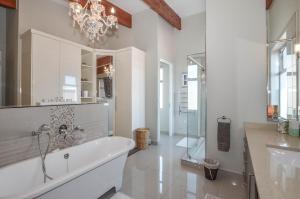 ein weißes Bad mit einer Badewanne und einem Kronleuchter in der Unterkunft 21 Flamingo House in Yzerfontein + 32 Fotos