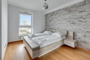 グダニスクにあるGrand Apartments - Luxury apartment on the 11th floor with a view of the Old Townの白いレンガの壁のベッドルーム(ベッド1台付)
