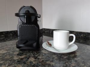 eine Kaffeemaschine und eine Kaffeetasse auf der Theke in der Unterkunft Córcega Palm Beach Salou - Piscina y Jardín in Salou