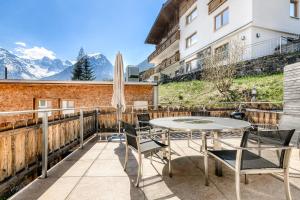 a table and chairs on a balcony with mountains at Ferienwohnung Zentral mit Panorama-Sonnenterrasse by A-Appartments in Brand