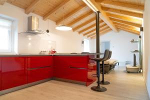 a kitchen with red cabinets and a black chair at Casa Vacanza Da Nonna Elena in Vattaro