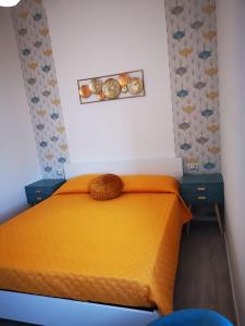 1 dormitorio con 1 cama con sábanas de color naranja y 2 mesas en Casa vacanza il Campanile, en Alghero