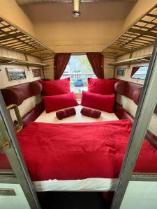 una cama en la parte trasera de una furgoneta con almohadas rojas en Übernachten im nostalgischen Bahnwaggon, en Bogen