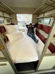 una persona sentada en una cama en una caravana en Übernachten im nostalgischen Bahnwaggon, en Bogen