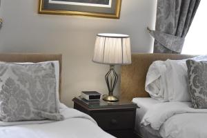 a hotel room with two beds and a lamp on a table at Anglers Arms in Alnwick