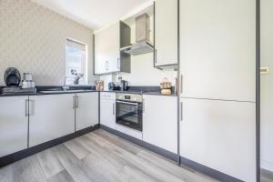 a kitchen with white cabinets and wood floors at Ash View Place 4 -Heathrow - Thorpe Park - Free Parking in Staines